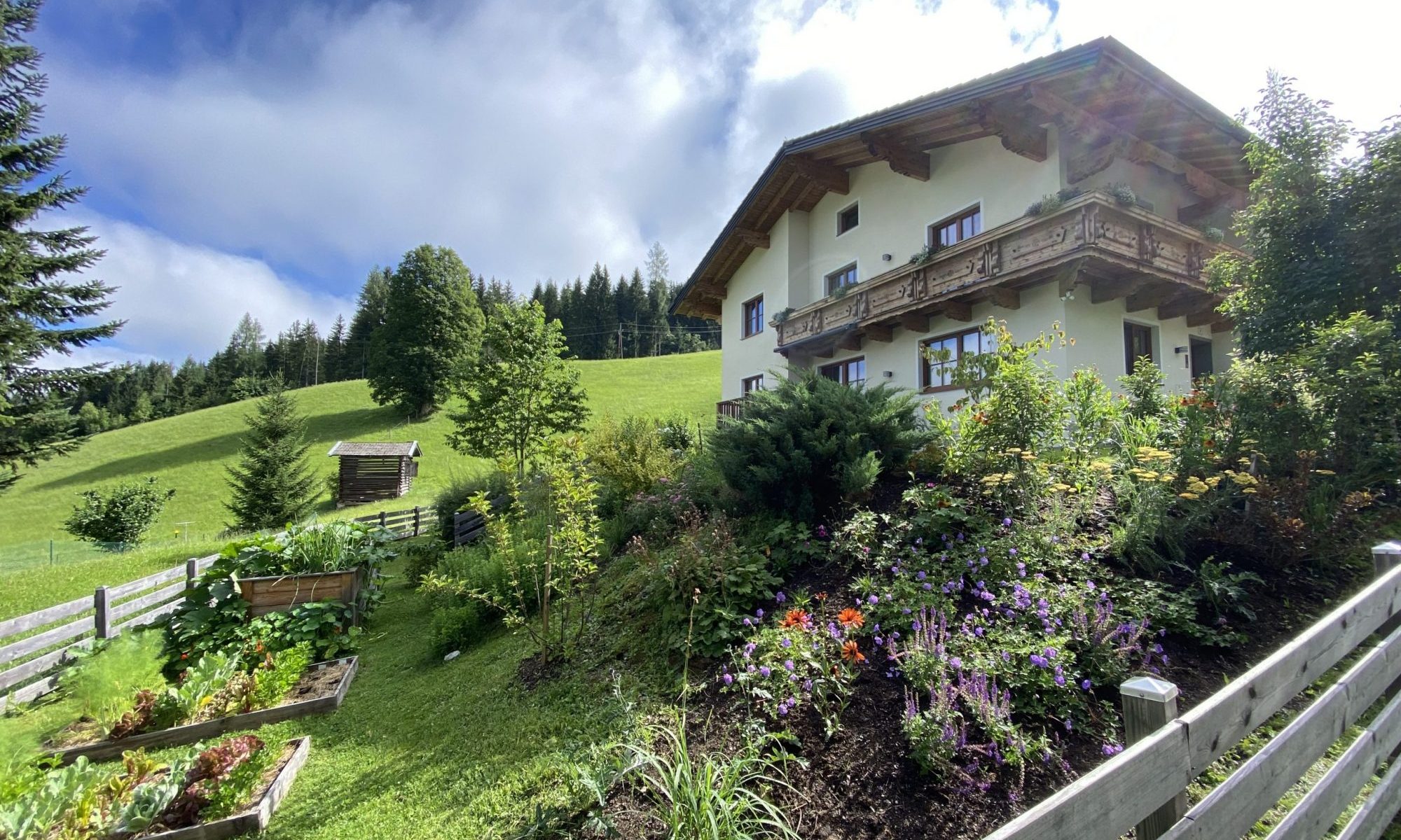 Oberleiten Apartments im Sommer mit dem Vorgarten und Gemüsegarten